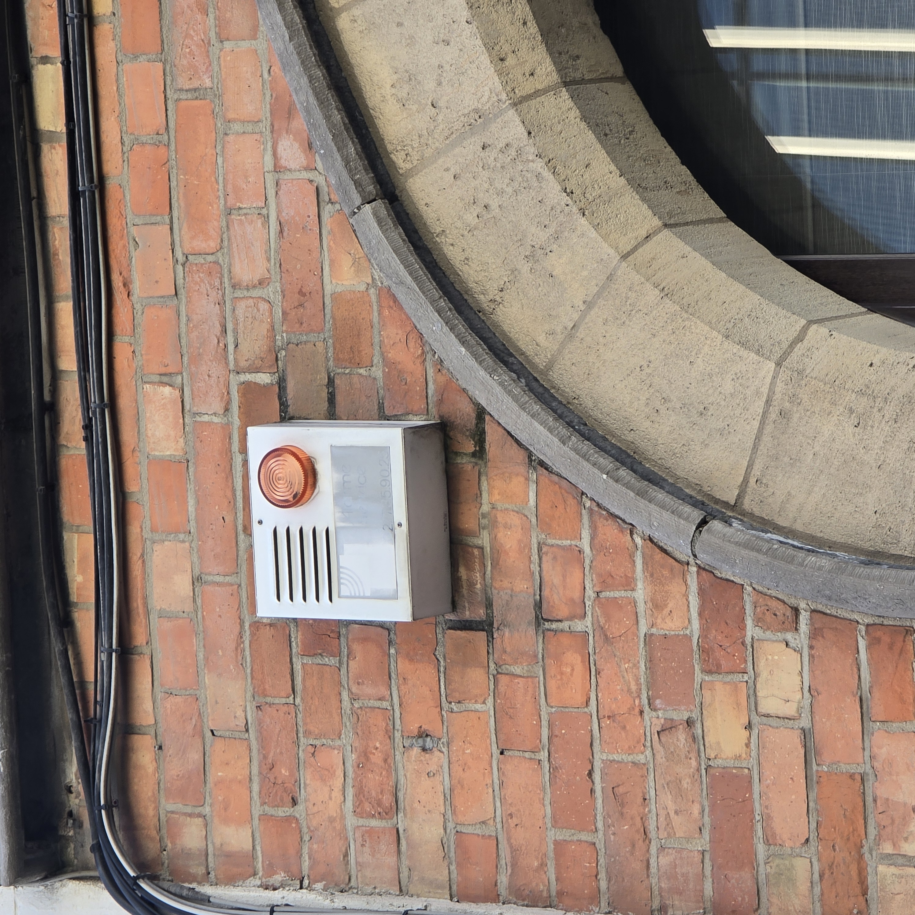 Sirène d'alarme intrusion extérieure ancienne sur façade en briques — déclenchement intempestif Bruxelles ELECOMM