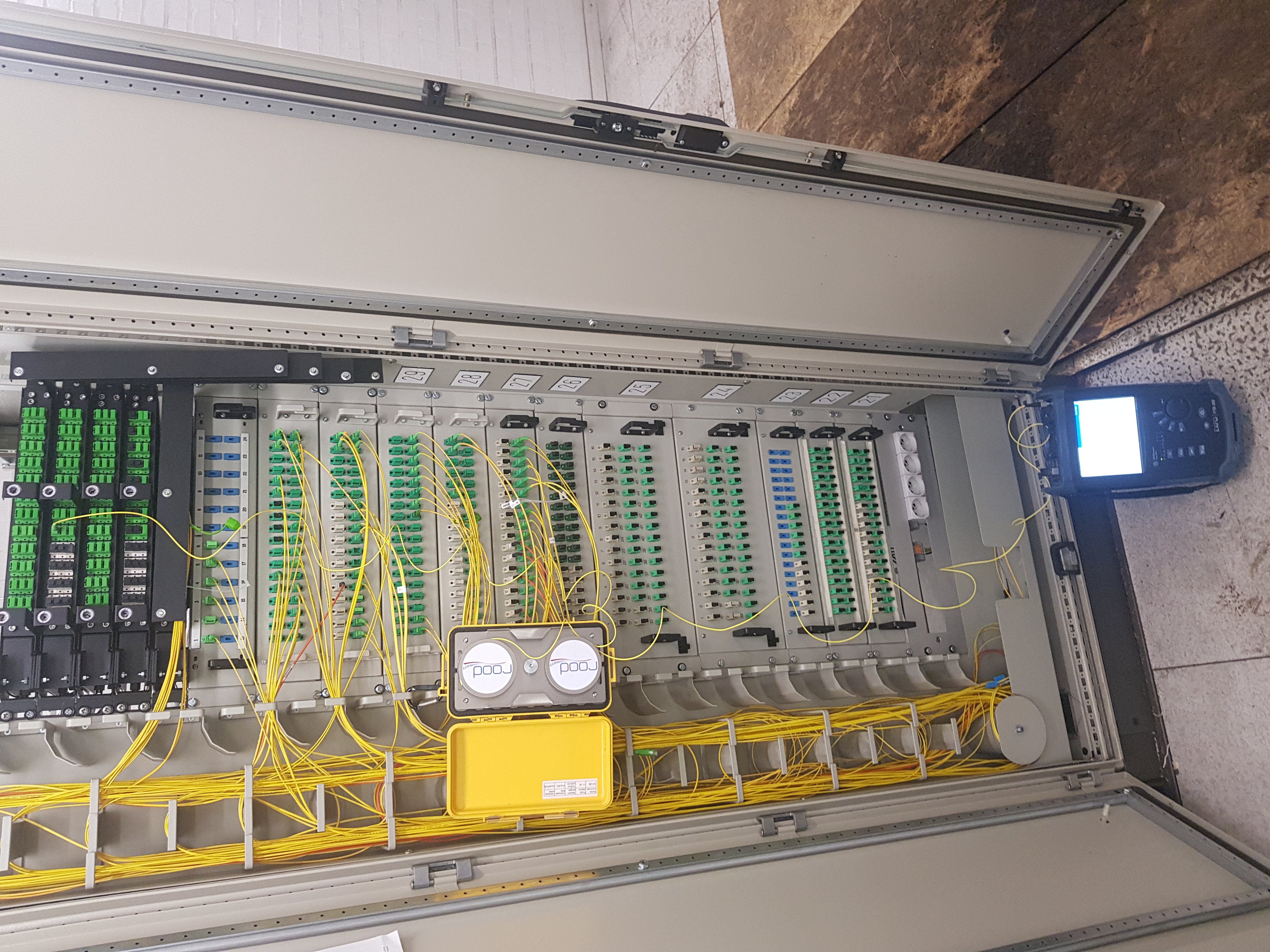 ODF rack 19 pouces fibre optique avec connecteurs SC/APC verts et OTDR au sol — diagnostic ELECOMM