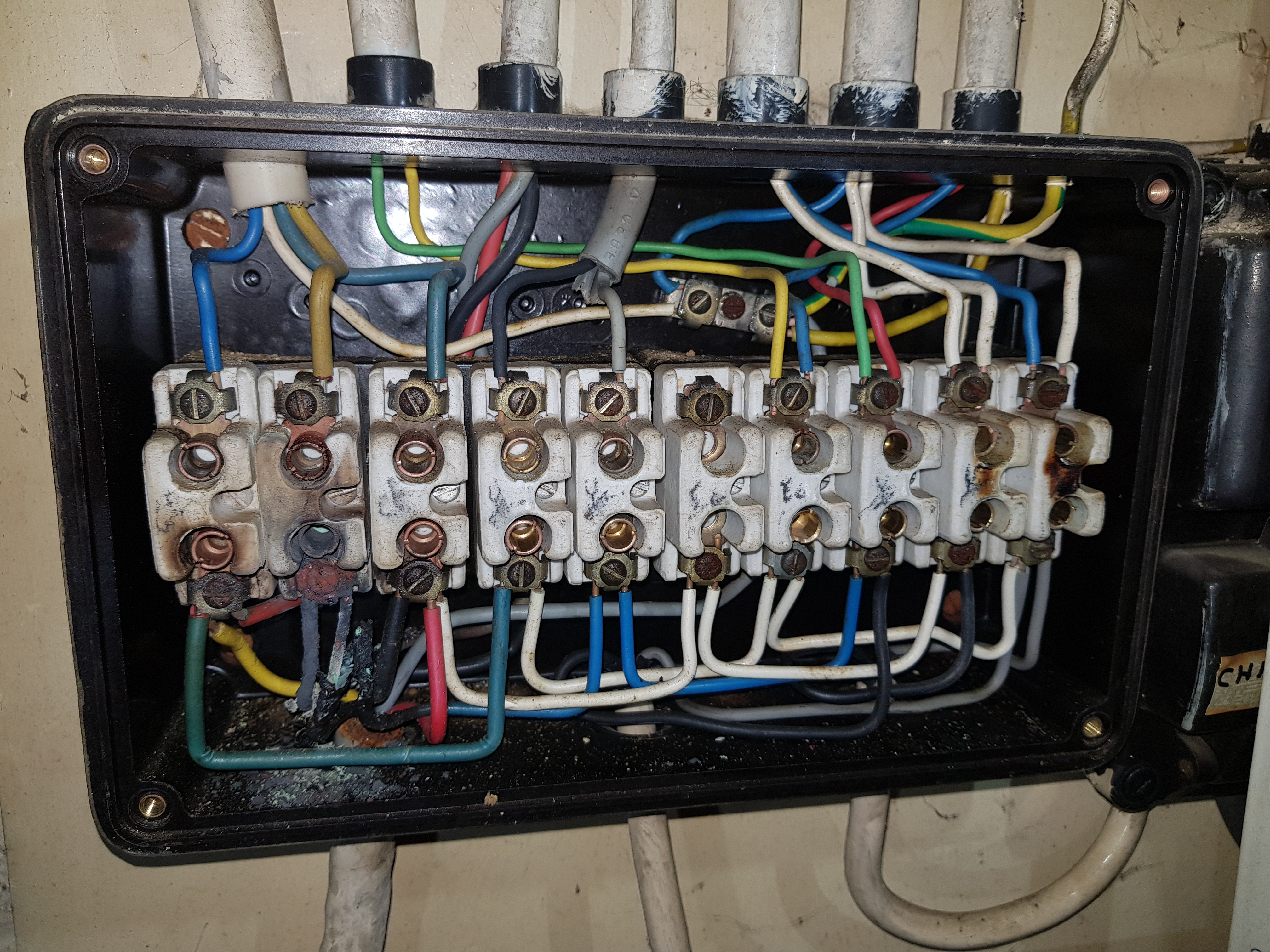 Vieux tableau électrique avec bornes céramique à vis et câblage multicolore ancien — risque incendie électrique Belgique